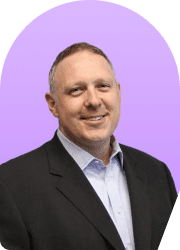 Headshot of a smiling man in a suit against a purple background.