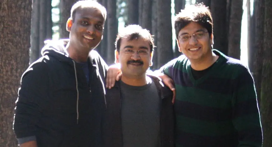 Three smiling colleagues stand together outdoors. About Us