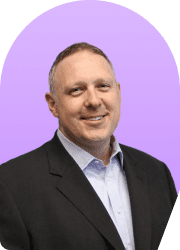 Headshot of a smiling man in a suit against a purple background.