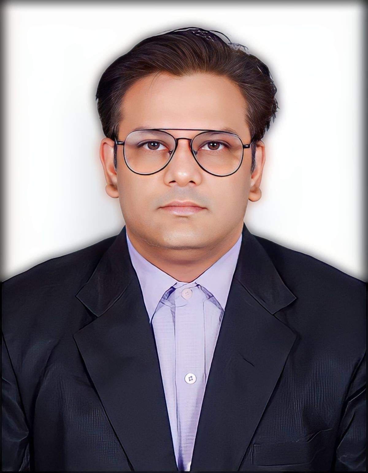 Headshot of a man in a suit and glasses